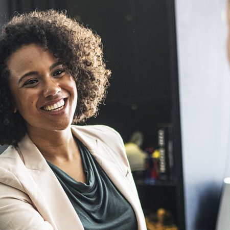 基本のビジネス英語「自己紹介」について解説する記事中のイメージ画像です。笑顔で談笑する女性の姿が写っています。