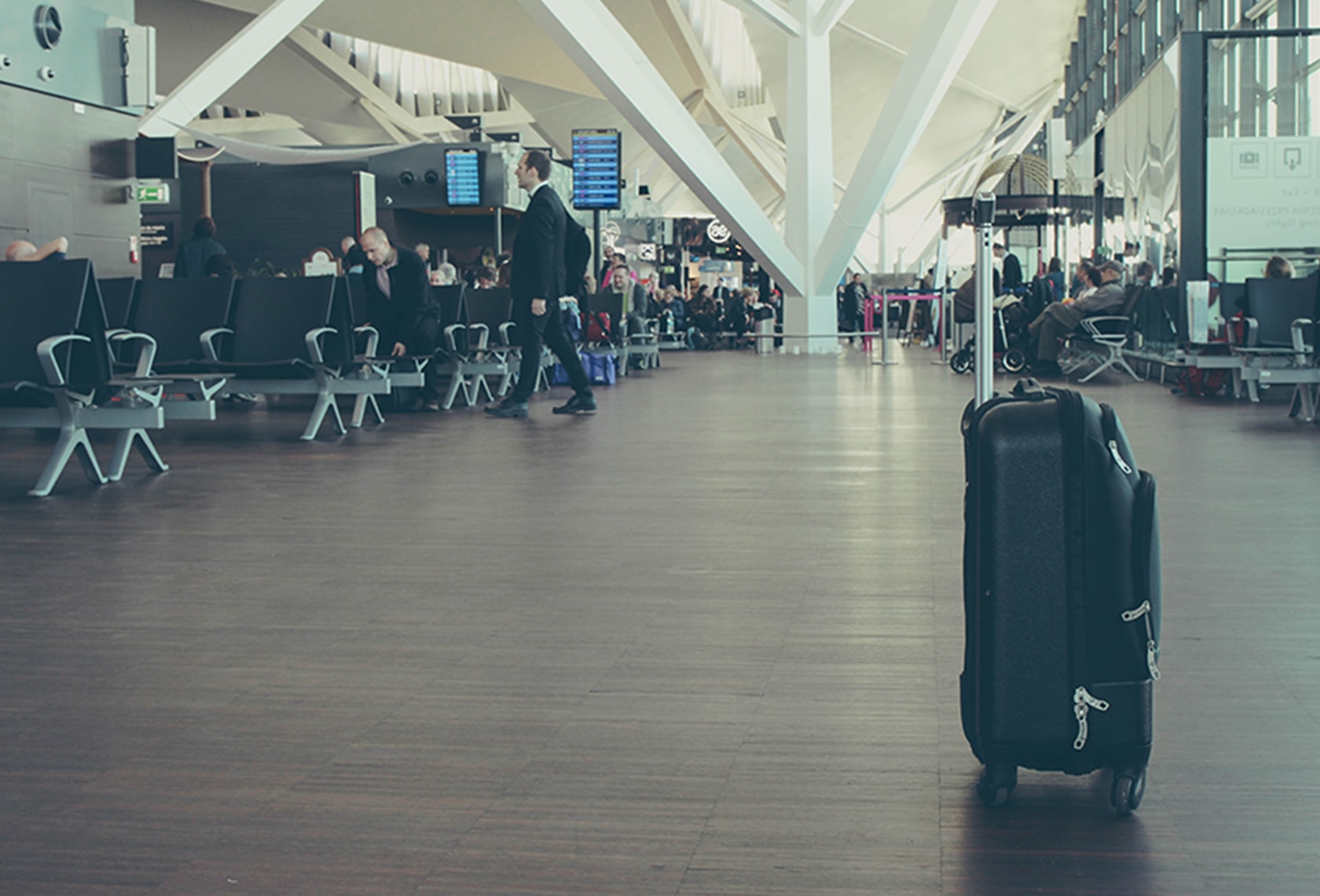 海外出張時などで持っていくスーツケースのサイズの選び方について解説した記事中のイメージ画像です。空港ロビーに置かれたスーツケースを写しています。