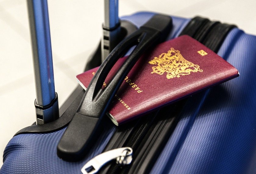 海外出張の必需品について書かれた記事中のイメージ画像です。スーツケースの上に赤いパスポートが置かれています。